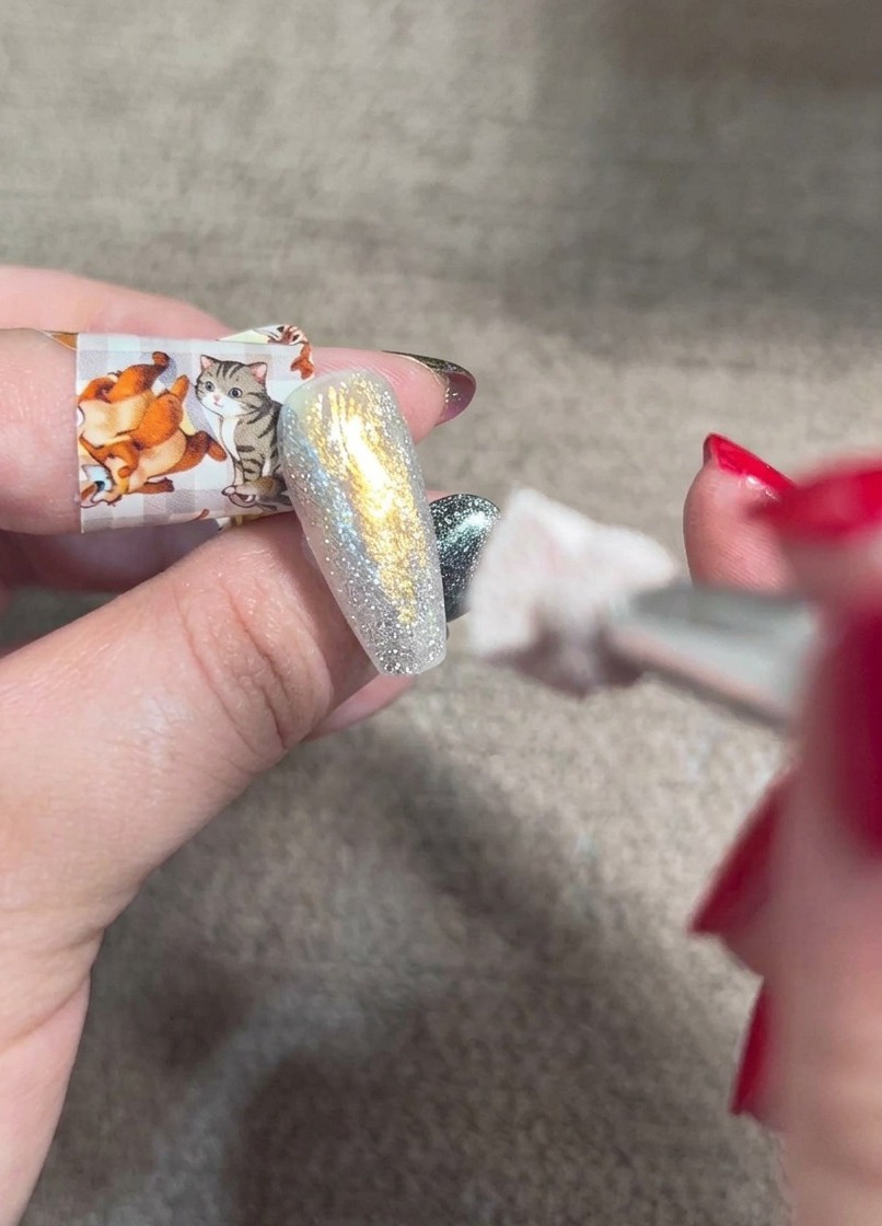 輝きのあるネイルの上に、オレンジのチークジェルをブレンディングブラシでポンポンとぼかしている様子。
