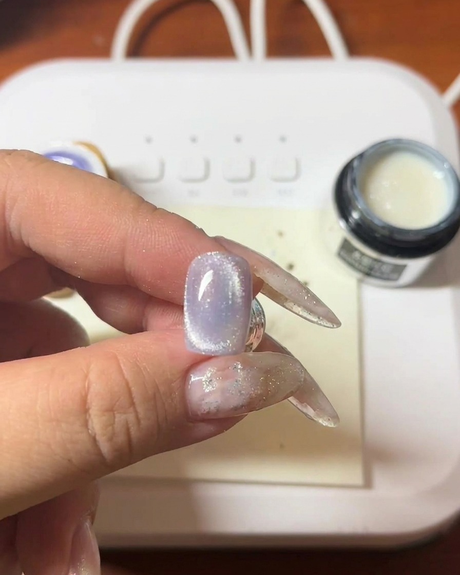 マグネットワンドを使い、パープルのジェルに光の筋を作っている様子。