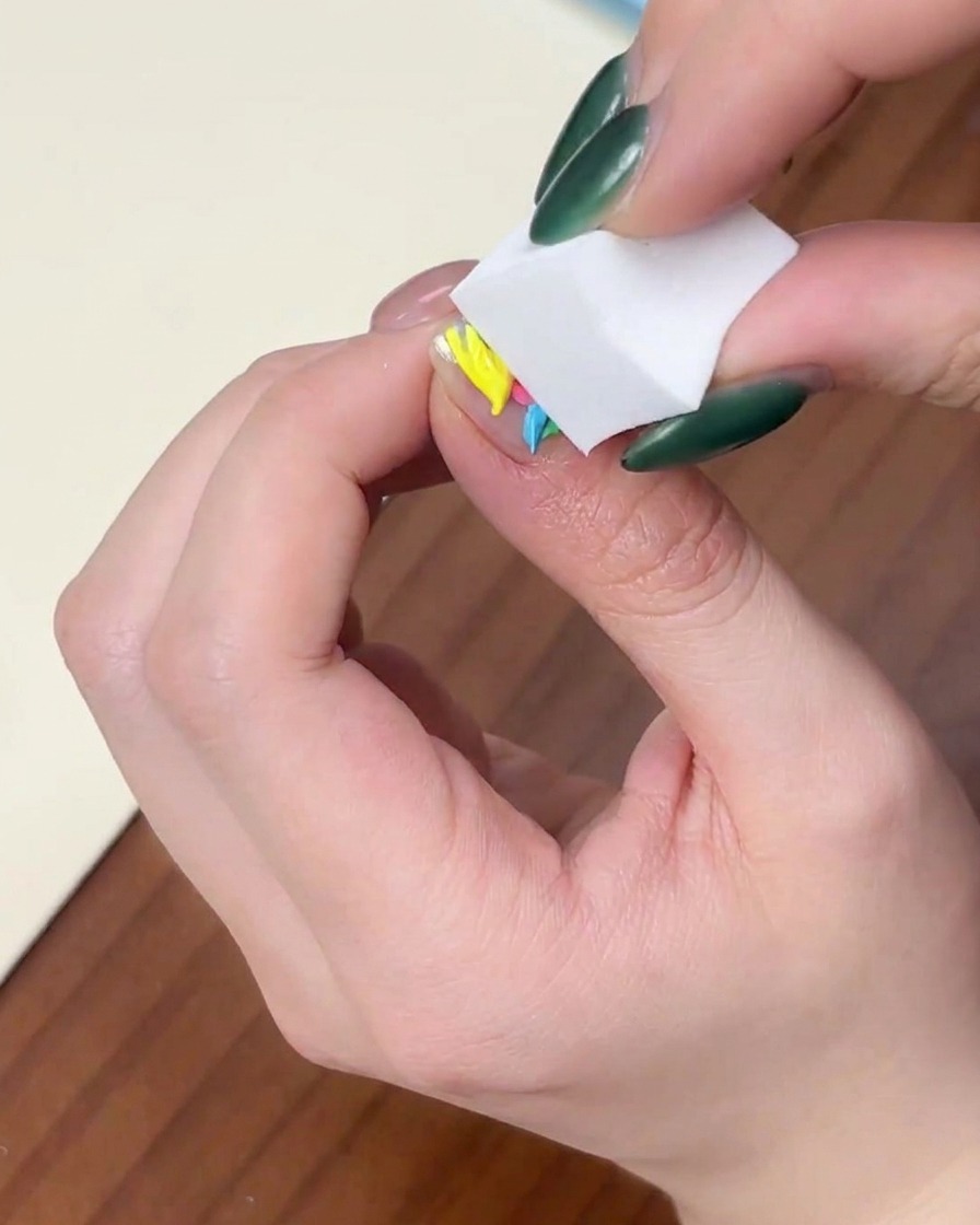 長方形のメイク用スポンジを爪の上のカラージェルに垂直に押し当てている様子