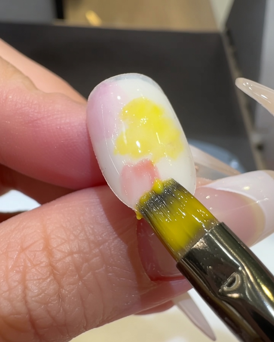 平筆でネイル表面のピンクとイエローの境目をぼかしている様子。