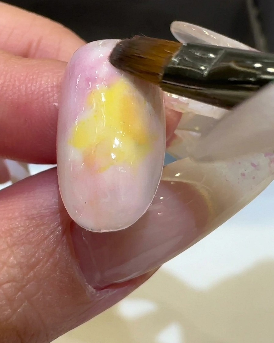 小さなネイル筆でイエローを重ね、色味を強めている様子。
