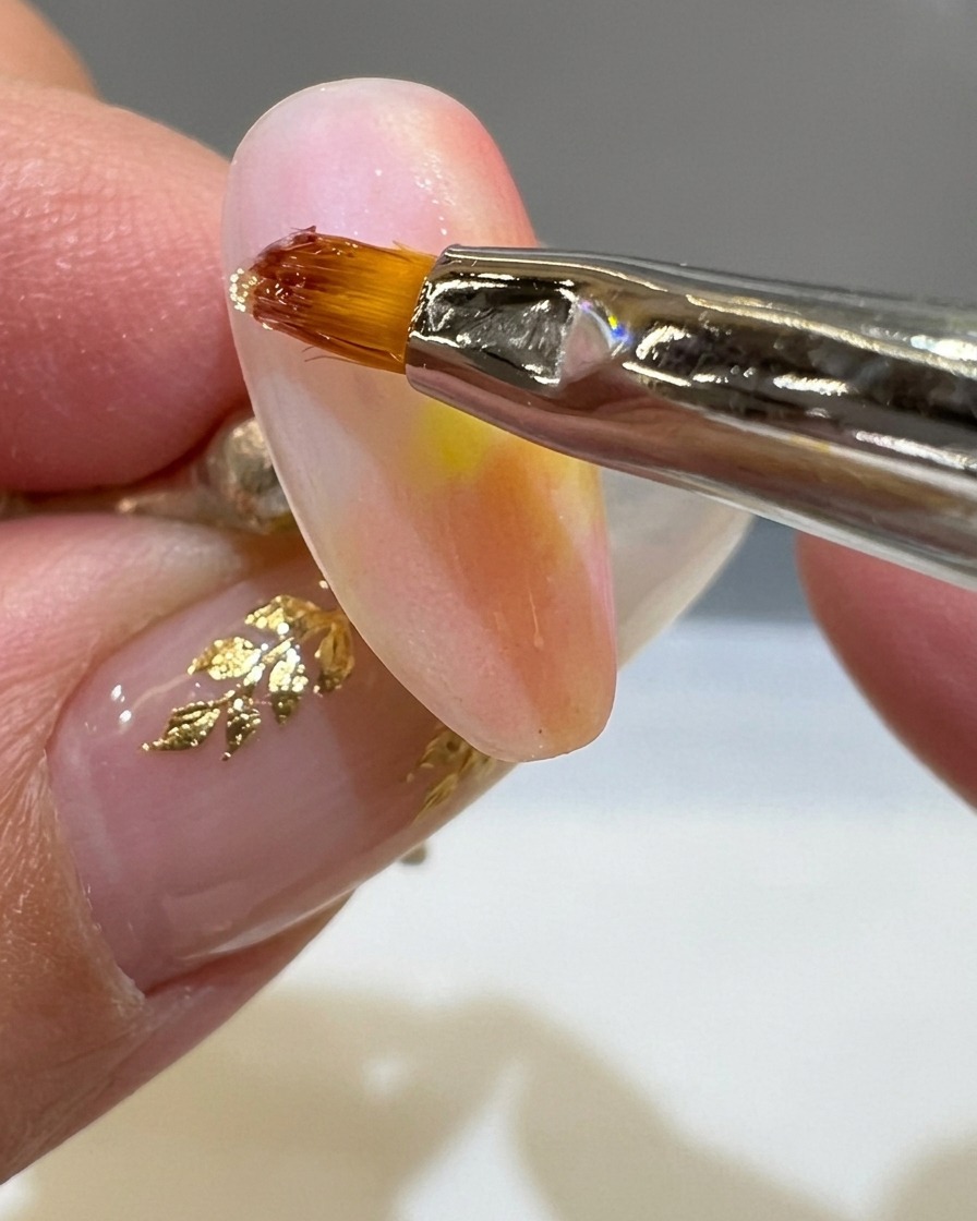 細いライナー筆でマットなネイルの上に透明な3Dジェルで波を描いている様子。