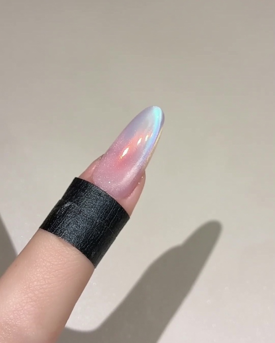 ベースカラーを塗った爪の上に、きらめく半透明のキャットアイジェルをブラシで塗布している様子。