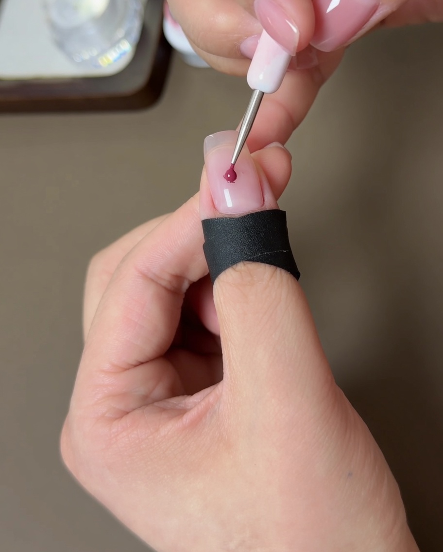 ヌードカラーの爪の中心に、ピーチカラーのジェルを少量乗せている様子。