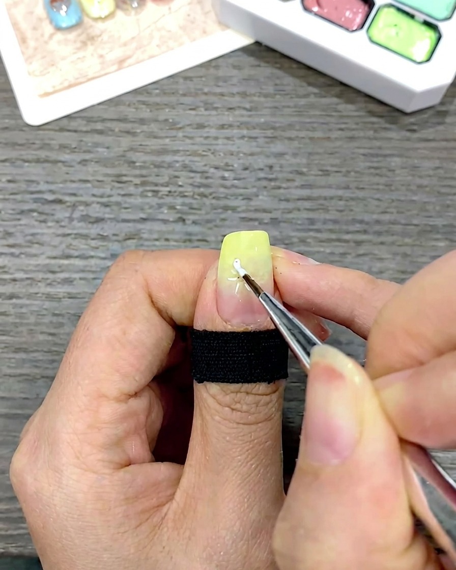 細筆を使い、中心の目印に向かって白い花びらを描き込んでいる様子。