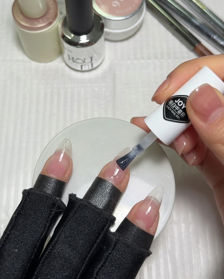 ヌードジェルを塗った爪の半分に、ミルキーホワイトジェルを塗布している様子。