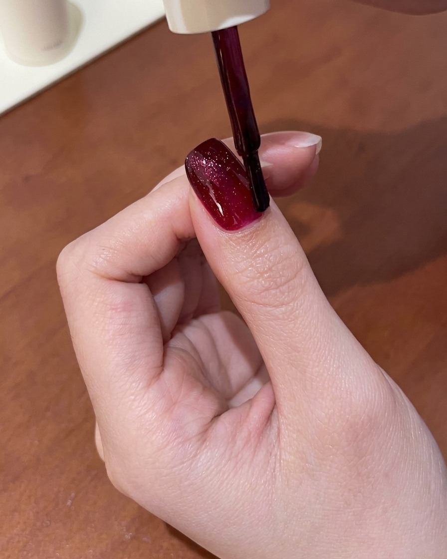 硬化前のレッドのキャッツアイジェルの上に専用マグネットをかざし、輝くラインを引き出している様子。