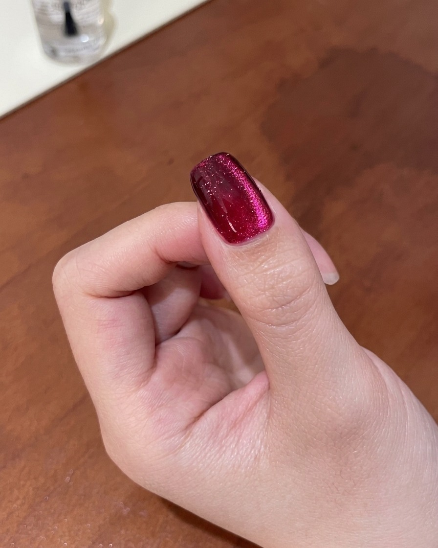 マグネットを使って輝きのラインをぼかし、深みのあるグラデーションキャッツアイの質感を整えている爪のクローズアップ。
