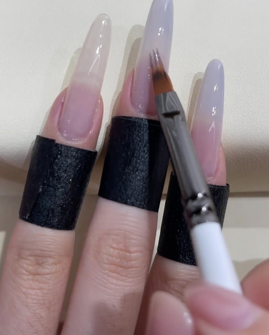 専用のオンブレブラシでグレーブルーのジェルを爪の下方へぼかしている様子。