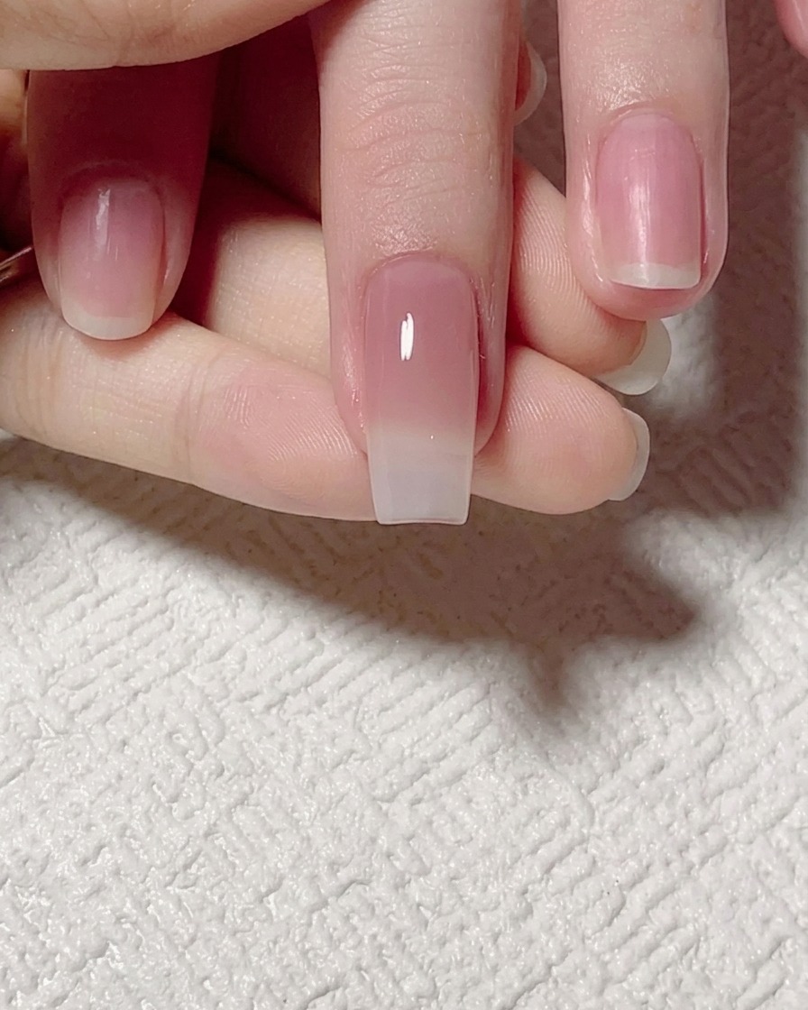 平筆を使い、ジェイドトーンのジェルを爪先に向かって引き伸ばし、滑らかなグラデーションに整えている様子。