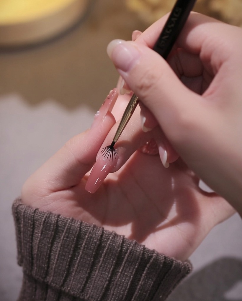 ライナーブラシで甘皮周りのピンクジェルを慎重に整えている様子