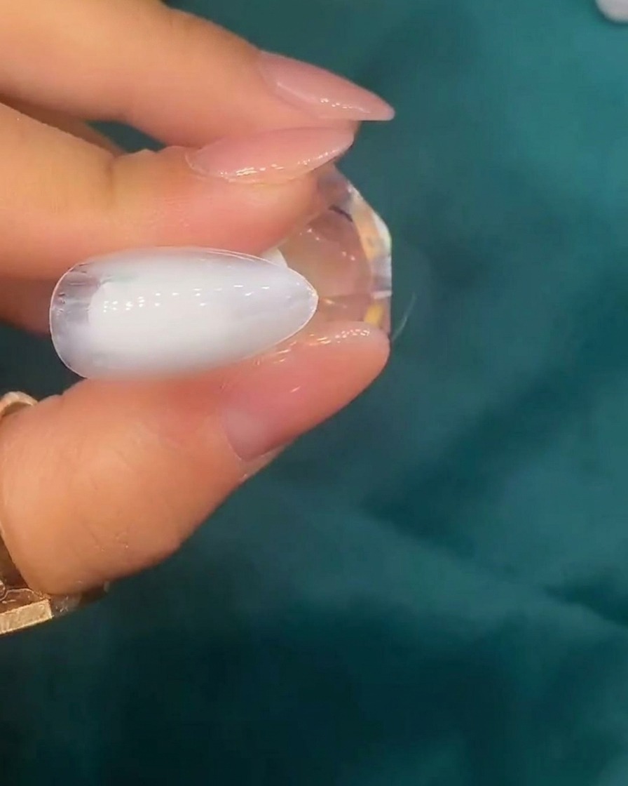 ピンセットで乳白色のジェルの上に小さなシェルを乗せている様子