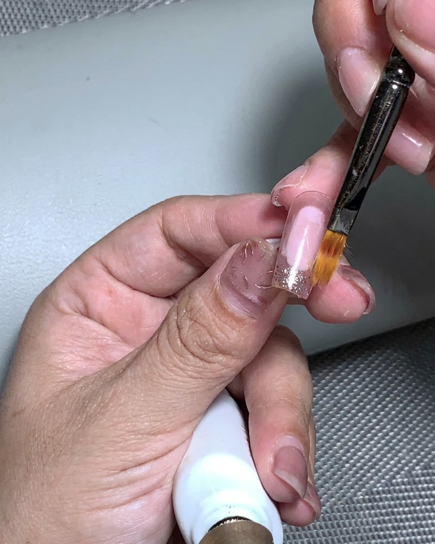 金箔を乗せた爪をUVライトで硬化している様子。