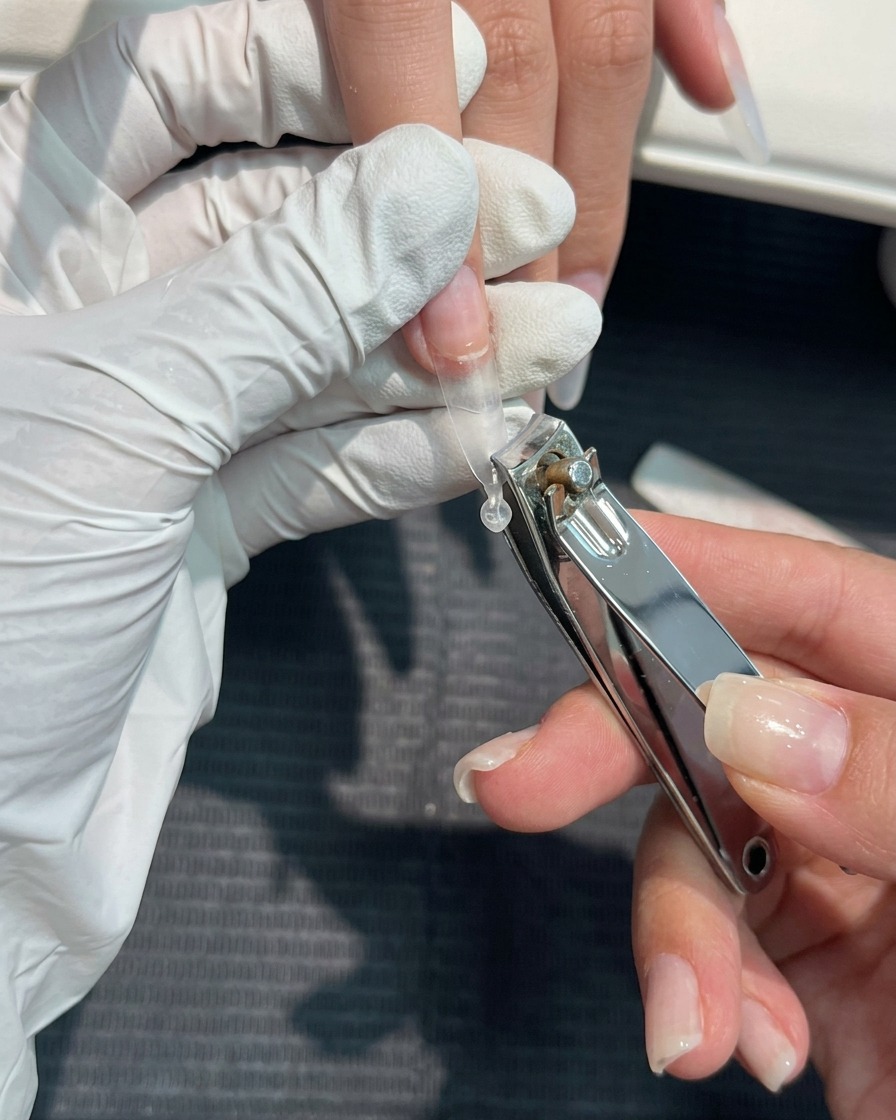ネイルクリッパーでクリアチップの長さを整えている様子。