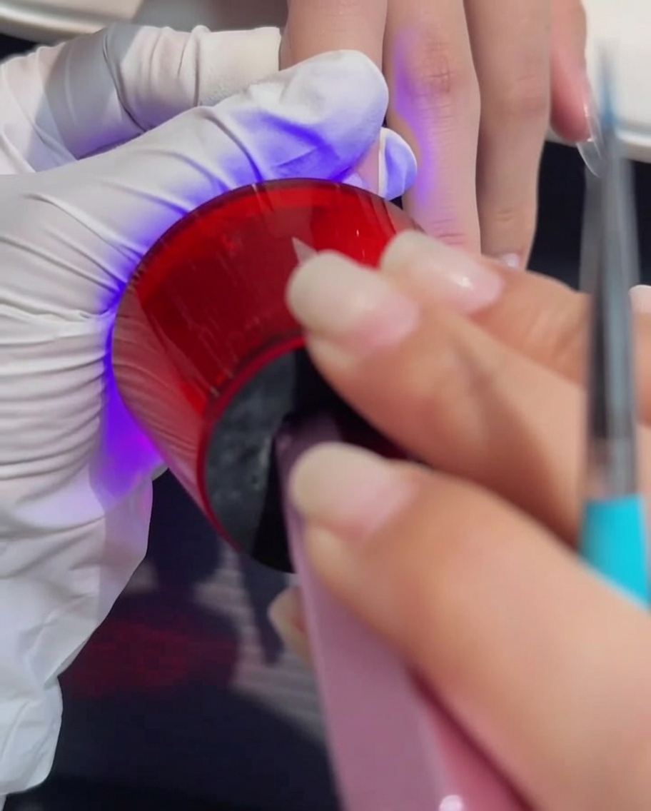 UV/LEDランプの中に手を入れてジェルを硬化させている様子。