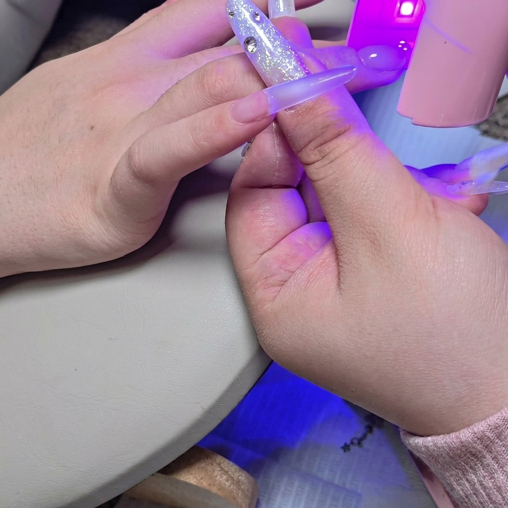 ミニUV/LEDライトを爪の上にかざし、2層目のビルダージェルを仮硬化させている様子。