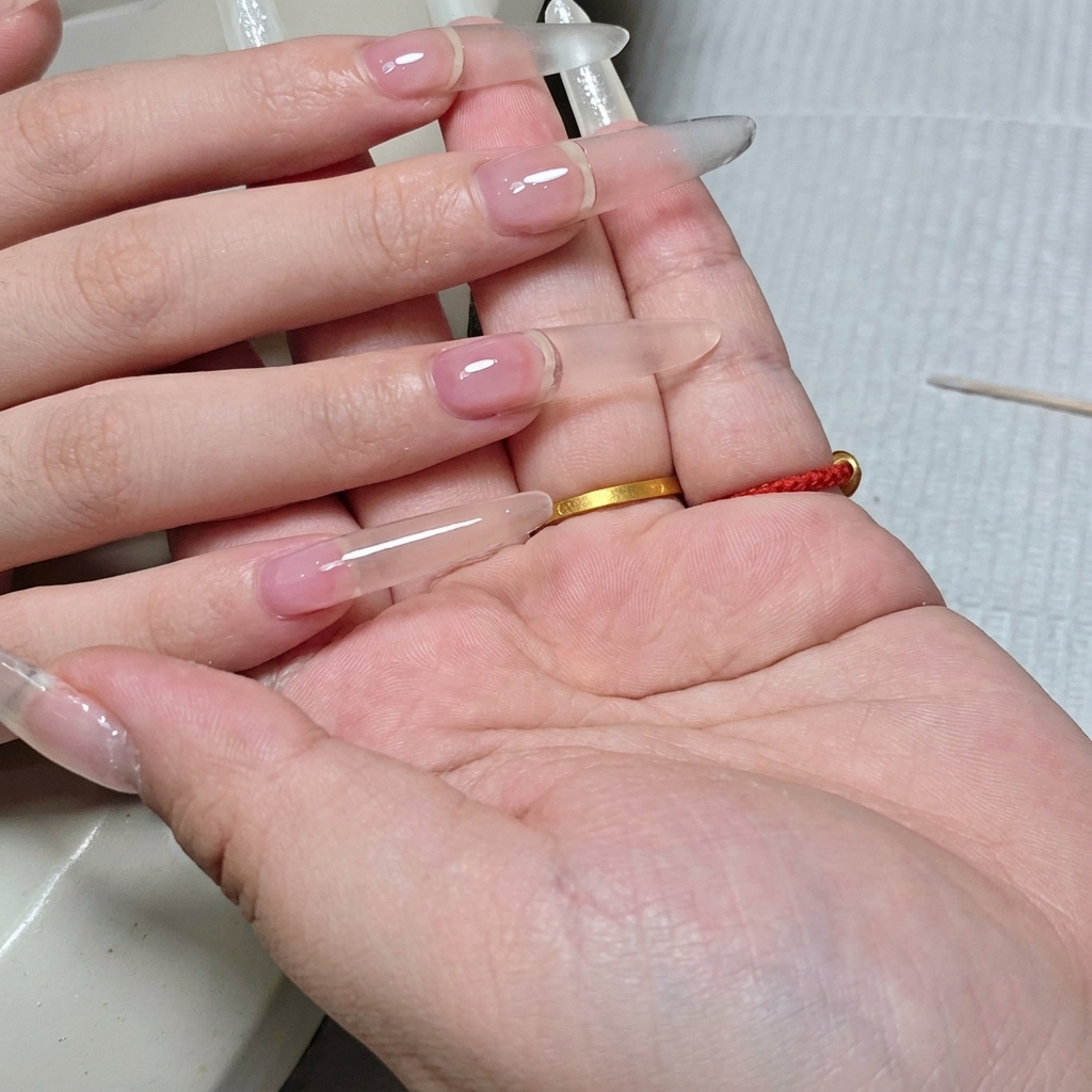 完成したクリアな長さ出しネイルを横から見た図。均一でぷっくりとした美しいアーチが確認できる。