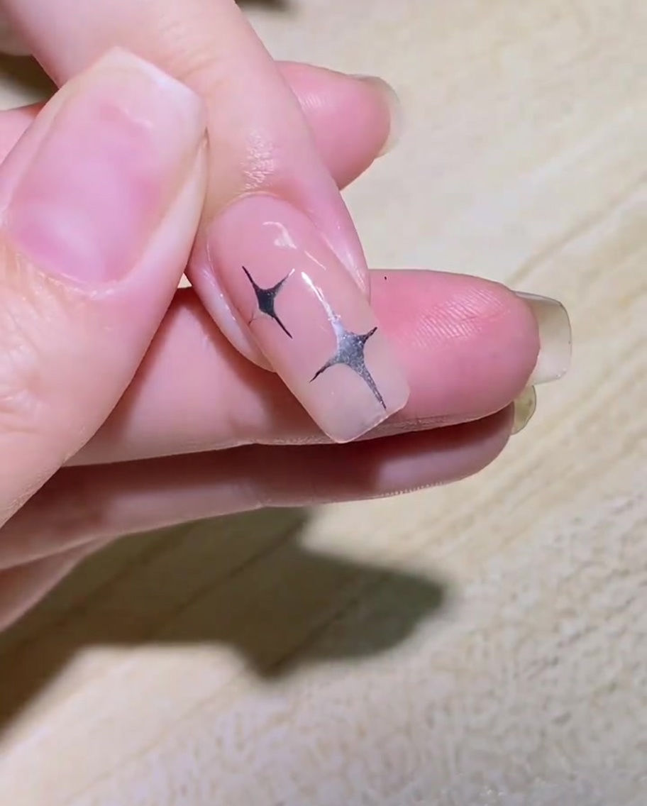 ネイルの端に沿ってライナーブラシで蝶の羽の曲線を描く様子。