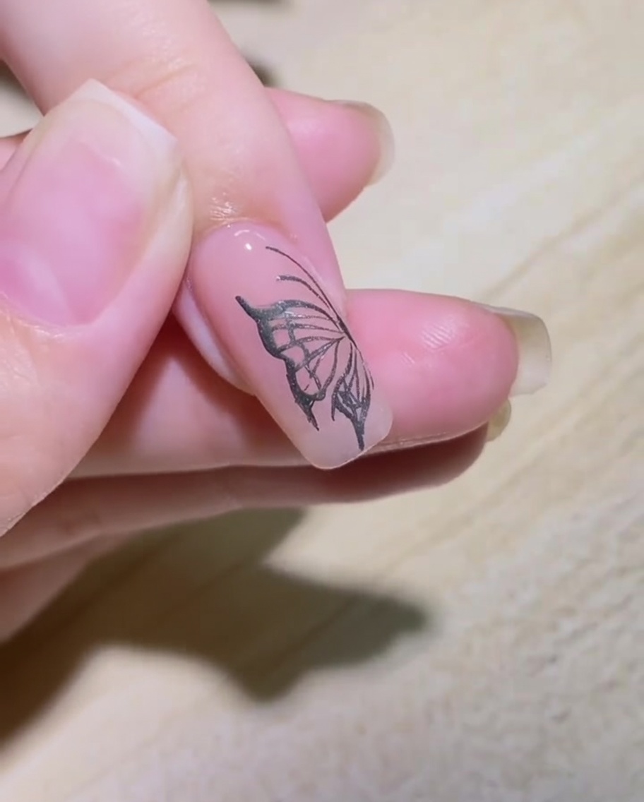 シルバーのメタリックジェルと細筆を使って、ネイルに炎のパターンを描き始めるアップ画像。