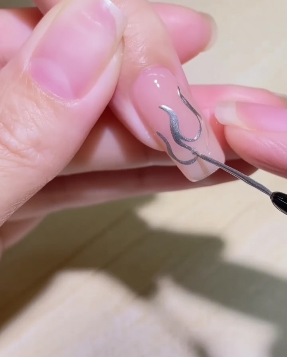 描かれた炎の輪郭の中をシルバーのメタリックジェルで埋めている様子。