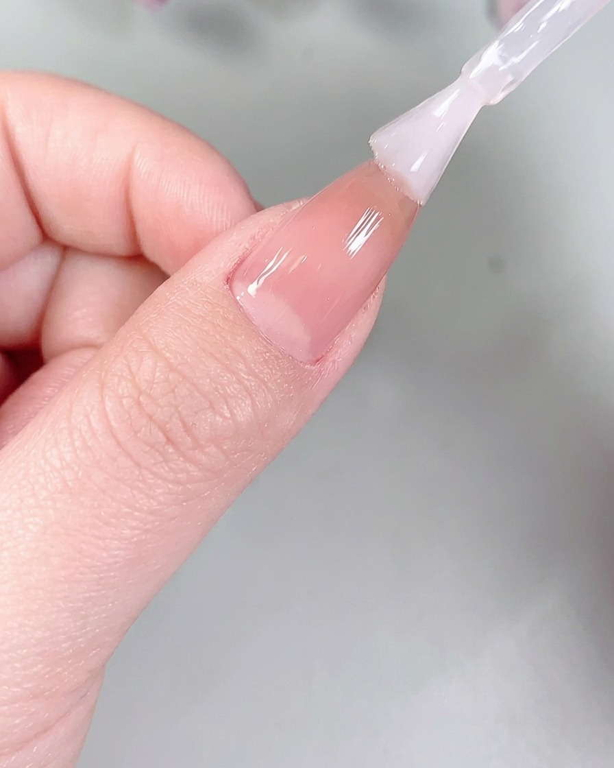 UV/LEDネイルライトの中に手を入れてマット層を硬化させている様子。