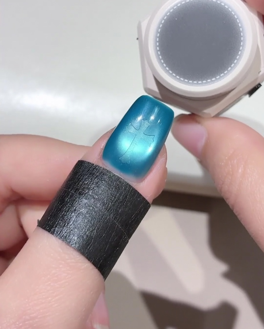 スポンジツールを使って、クロスステッカーが貼られた爪に黒いジェルを叩き込んでいる様子。