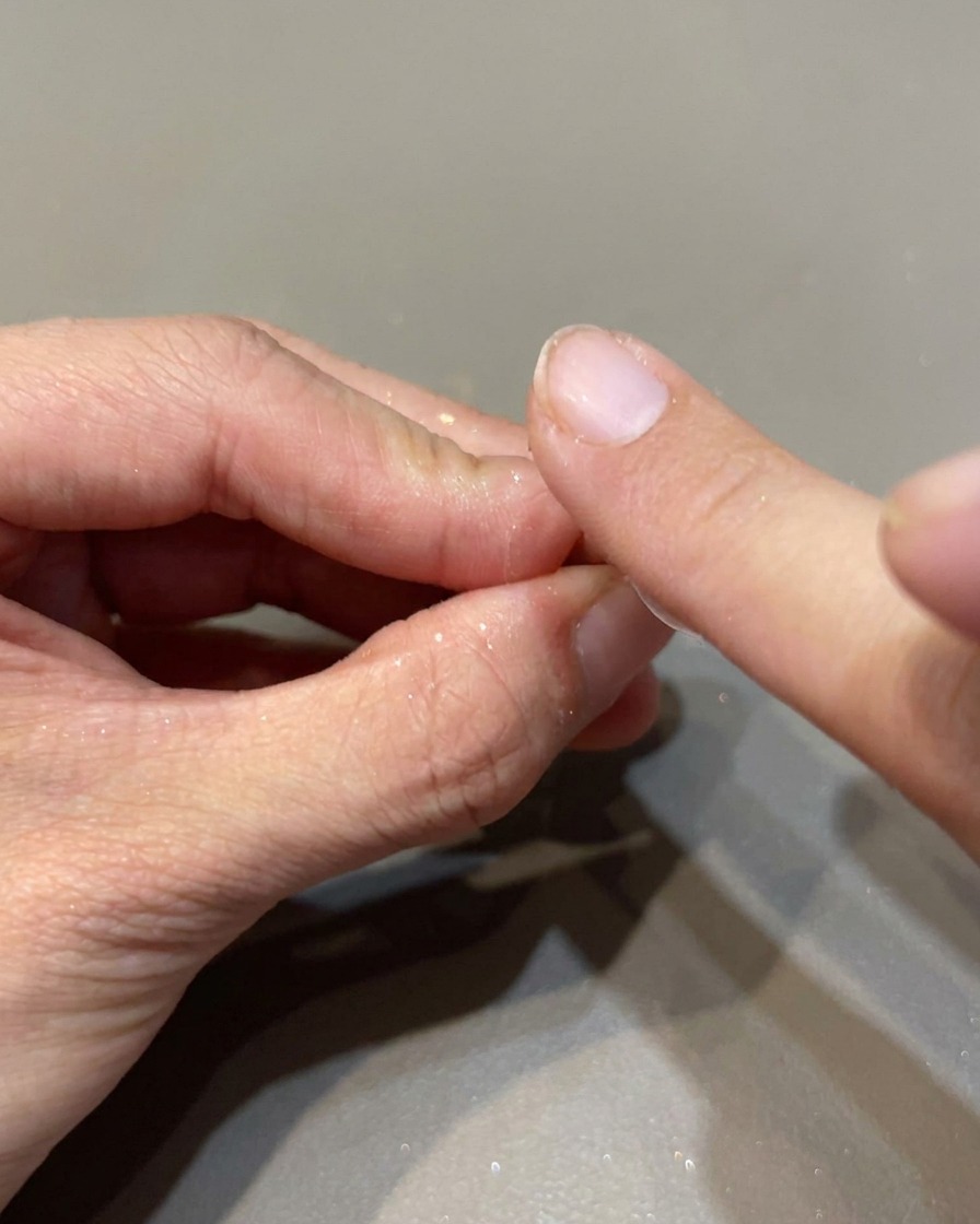 スポンジチップで虹色のミラーパウダーを爪に塗り込み、光沢を出している様子。