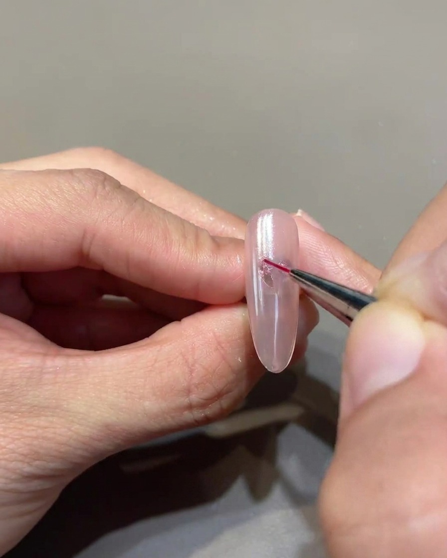 細いライナーブラシを使って、ハートの形をくっきりと整えている様子。