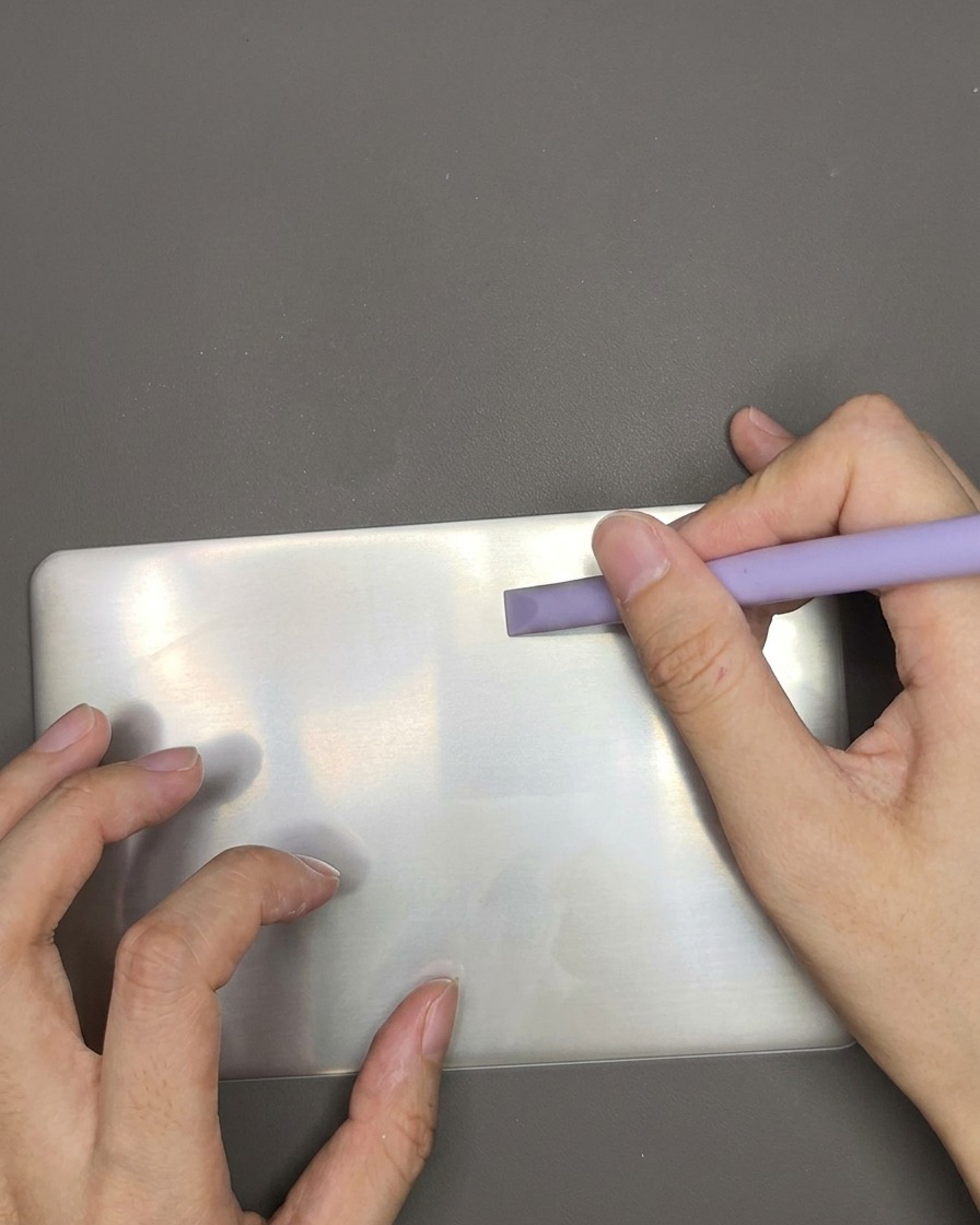 スクレイパーでスタンププレート上の余分なポリッシュを取り除いている様子。