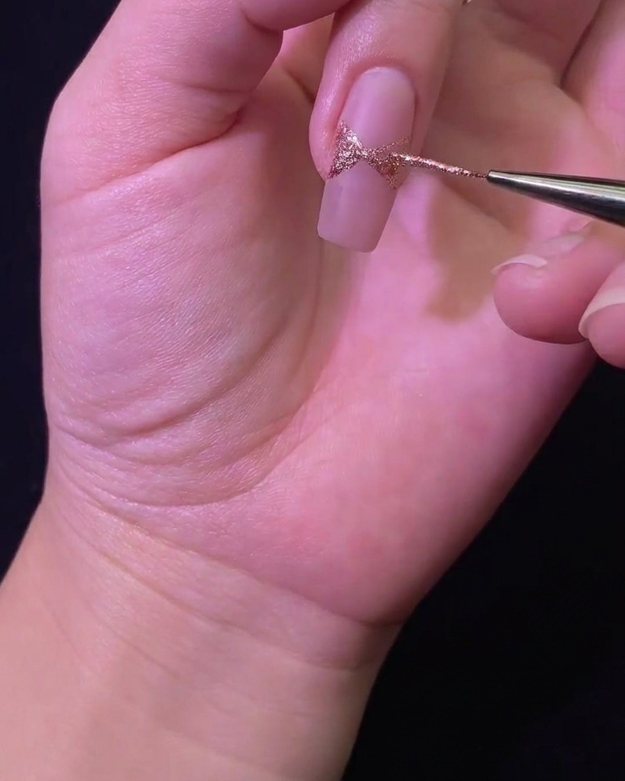 細筆を使ってグリッタージェルでリボンの形を塗りつぶしている様子。