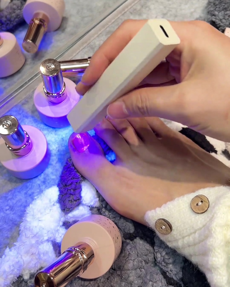 ハンディタイプのUV/LEDライトで親指のジェルを硬化させている様子。