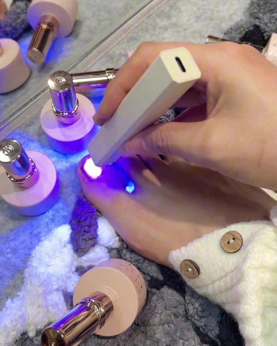 小さな指の爪にローズピンクのキャッツアイジェルを塗布している様子。