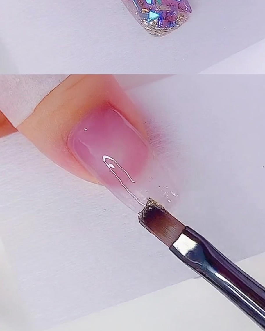 平筆を使い、爪の先端からローズゴールドのラメジェルを薄く塗り広げる様子。