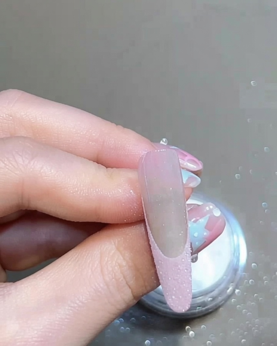 柔らかいブラシでネイルの上の余分なパウダーを払い、きれいなフレンチラインを見せている様子。