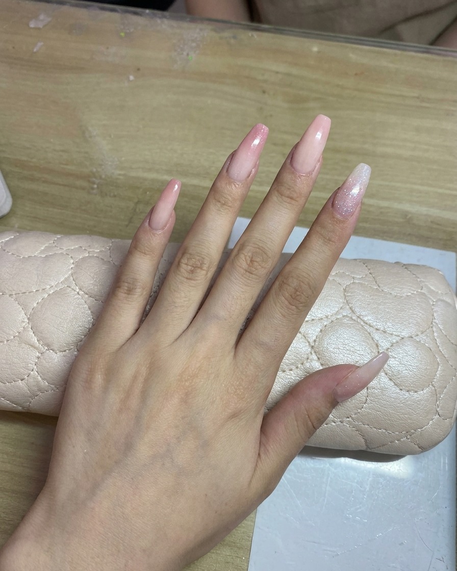 ロングネイルにエアブラシでピンク色の繊細なグラデーションを重ねている様子。