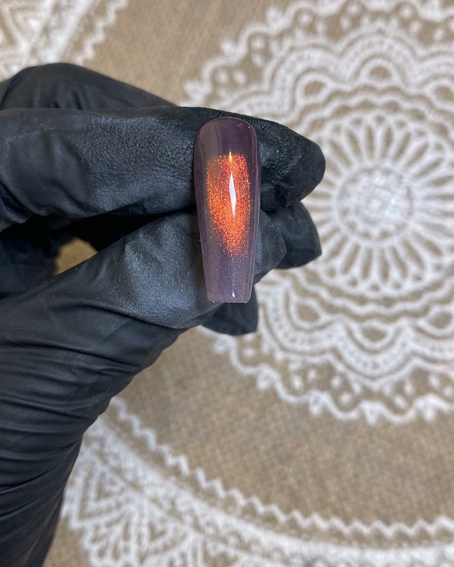 エアブラシノズルからホワイトの霧が爪へ噴霧されている様子。