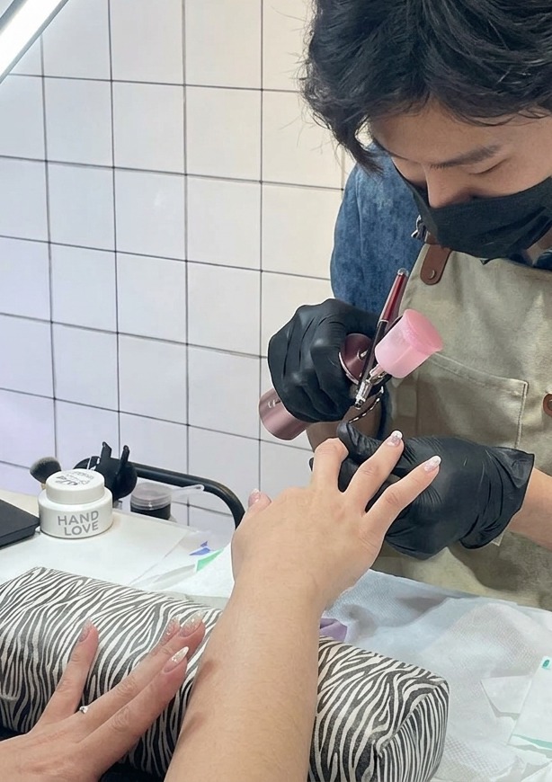 エアブラシからパープルの細かいミストが爪先に噴射されている拡大写真。