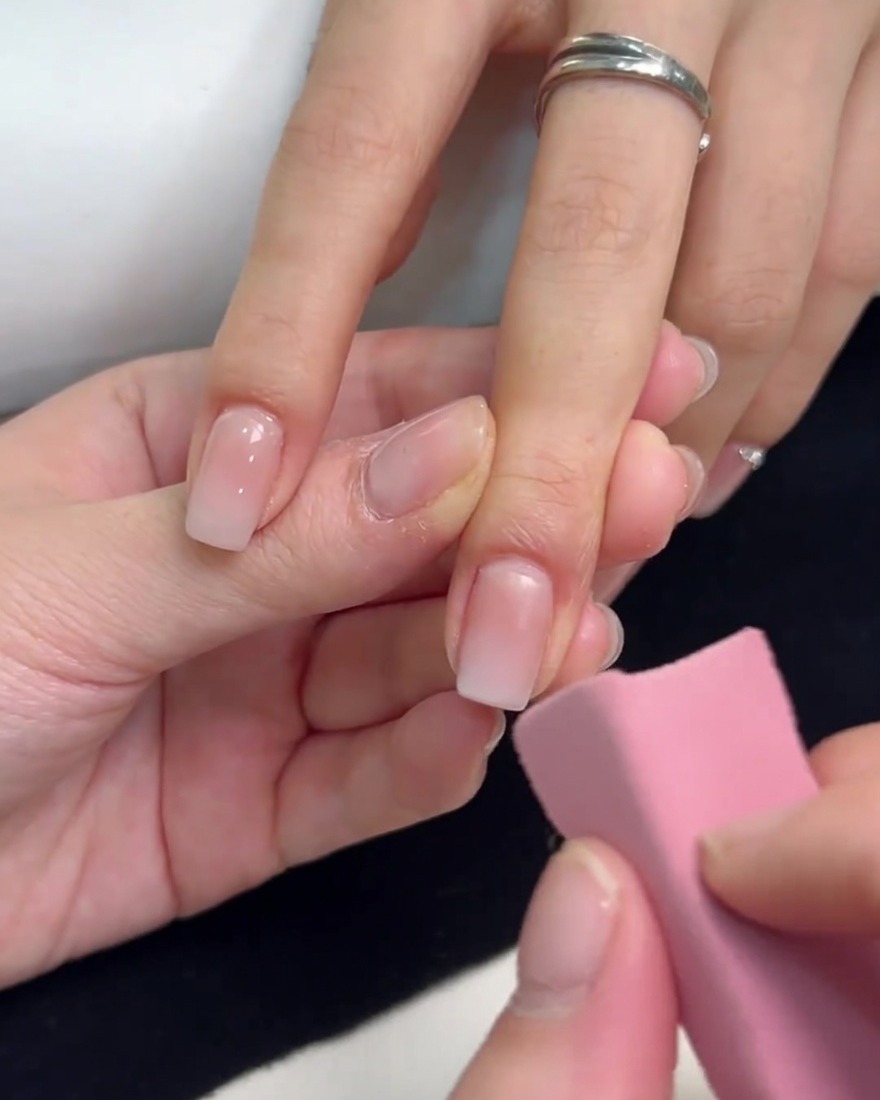 ピンクのスポンジを使い、スクエアの爪の先端からホワイトジェルをポンポンと叩いてグラデーションを作っている様子。