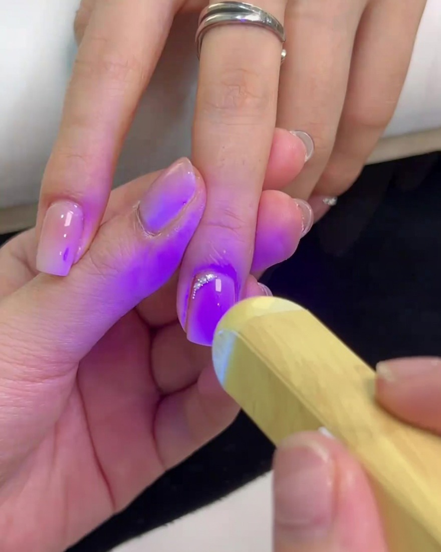 ハンディライトを使って、根元に並べたビジューを硬化させている様子。