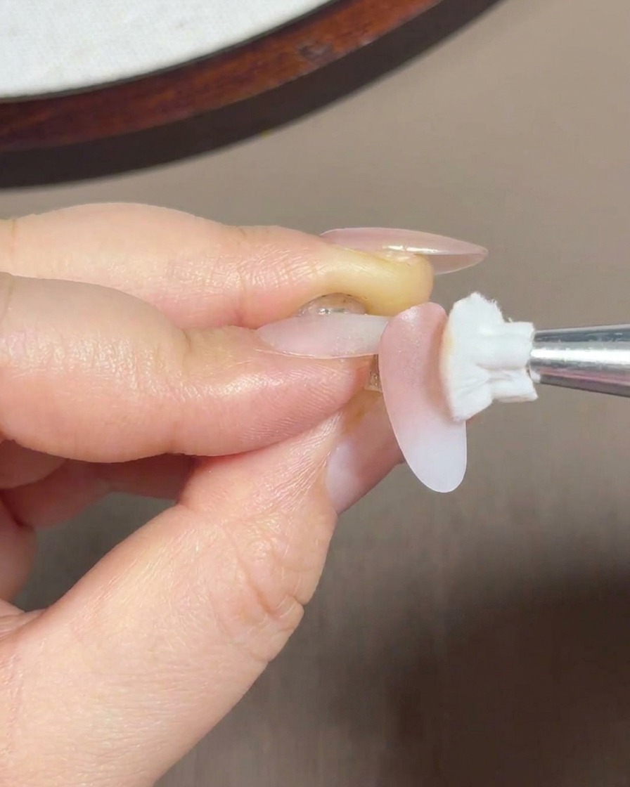 ブラシを使って、爪の中間から根元にかけてピンクジェルを馴染ませている様子。