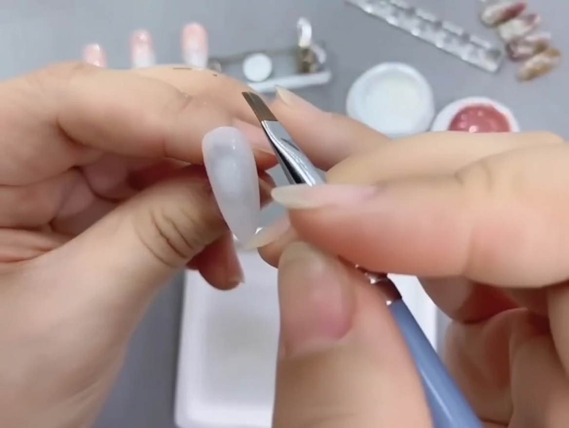 斜めカットのブラシでヌードジェルを爪の根元から塗布している様子