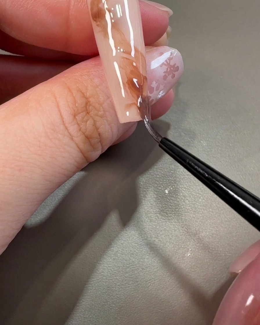 細筆を使ってブラウンジェルを左右に引き、マーブルの質感を作っている様子。