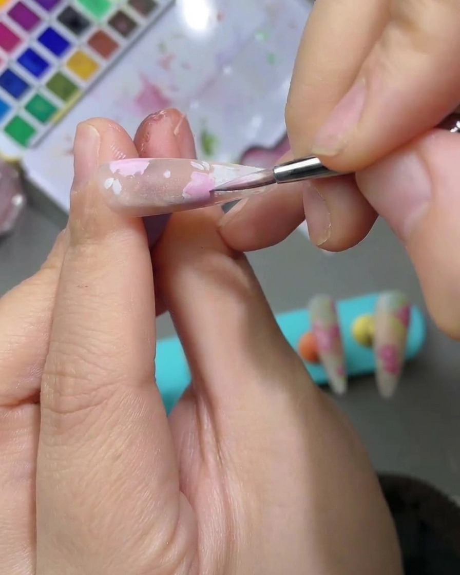 ピンクの花びらの隣に、淡いグリーンの水彩絵の具で葉を描いている様子。