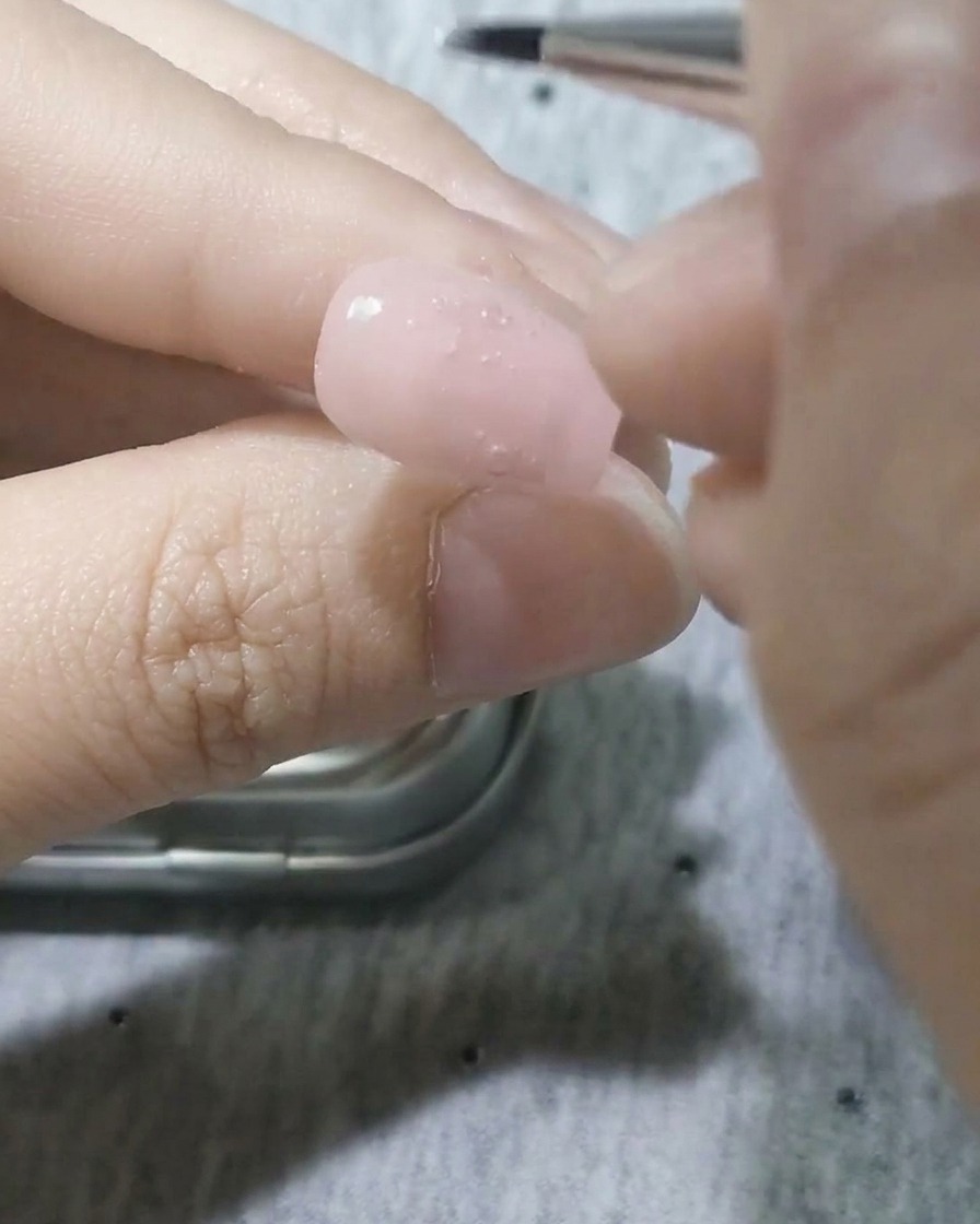 細い筆でホワイトジェルを使い、花びらの輪郭を描いている様子