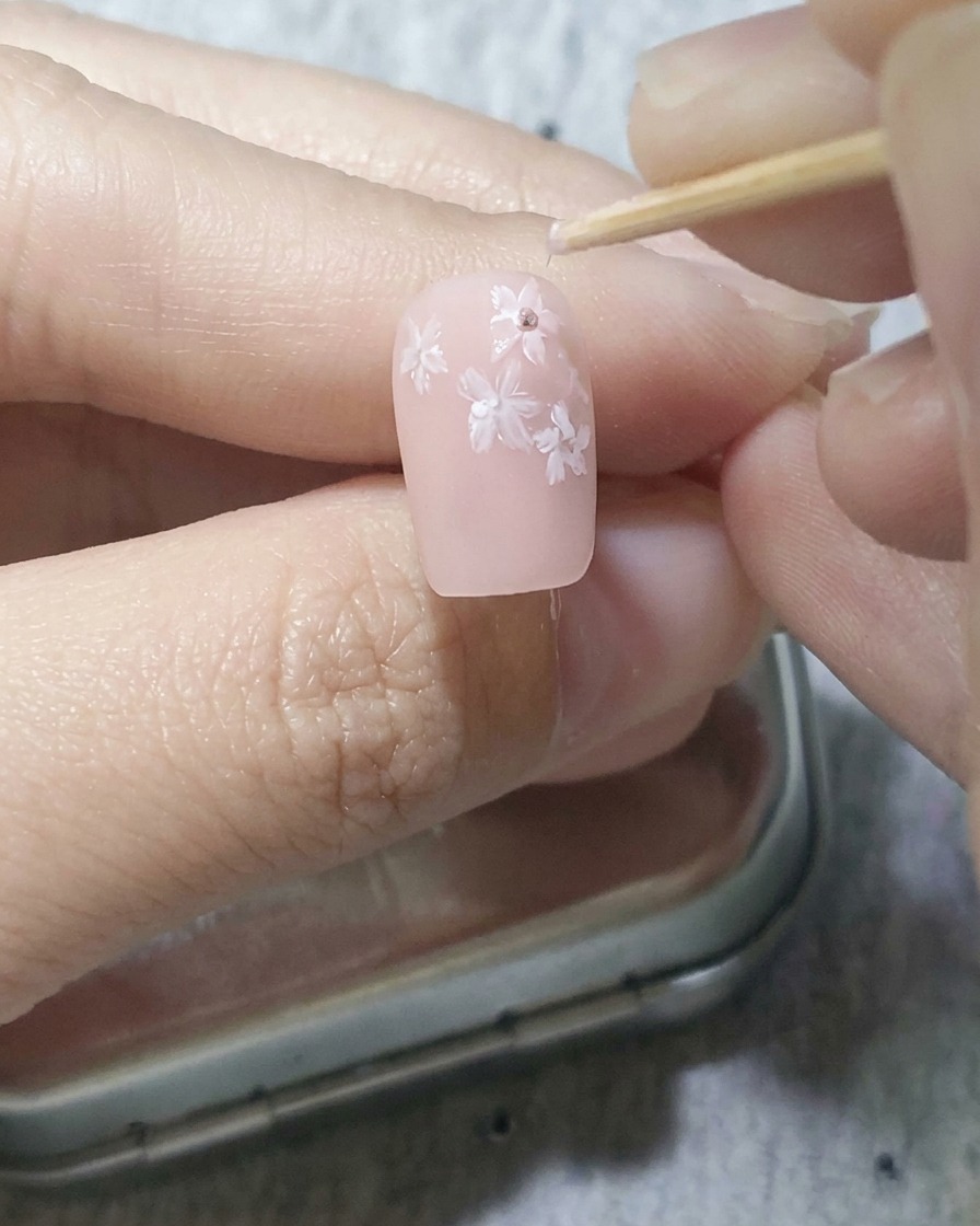 白い花の中央にピンクの点を置き、少しだけ外側に引っ張っている様子