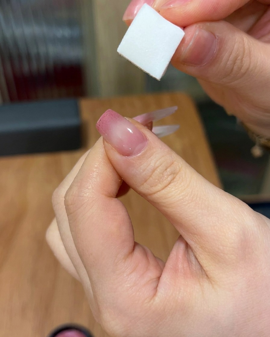 スポンジで爪にピンクのジェルを叩き込み、爪先から中央に向けてソフトなグラデーションを作っている様子。