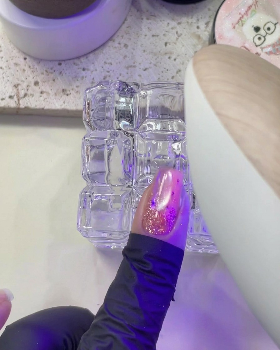 爪をUV/LEDライトの紫色の光の下で硬化させている様子。