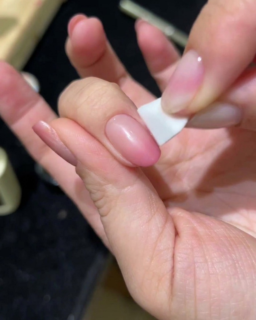 スポンジを使って2層目のピンクキャッツアイジェルを塗布している手。