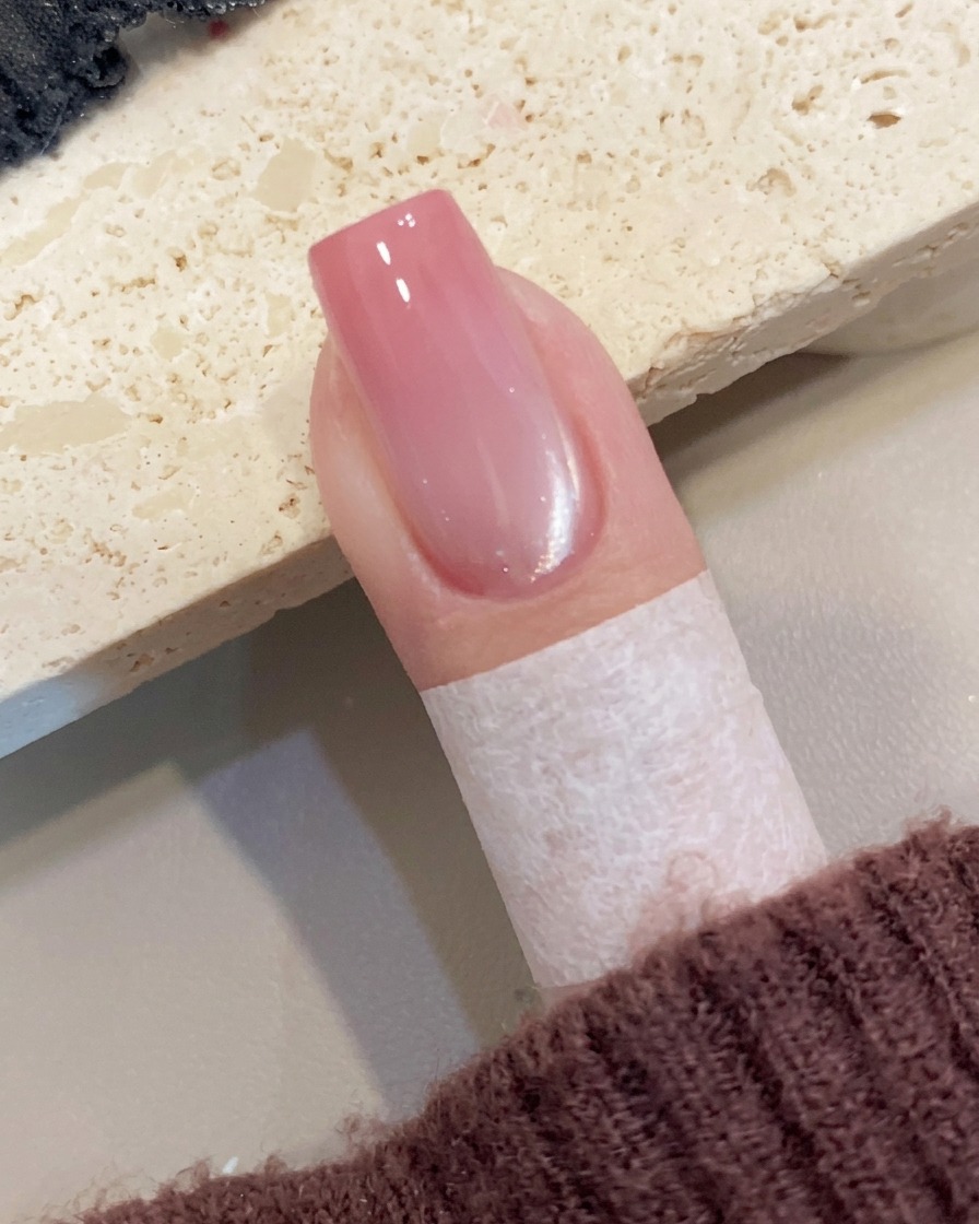 マニキュアを施した爪の周囲に貼られた保護用のマスキングテープを、指先で丁寧に剥がしている様子。