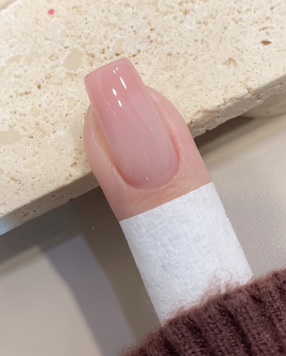 硬化後のジェルネイル表面に残った未硬化ジェルを、リントフリーワイプで優しく拭き取っている様子。